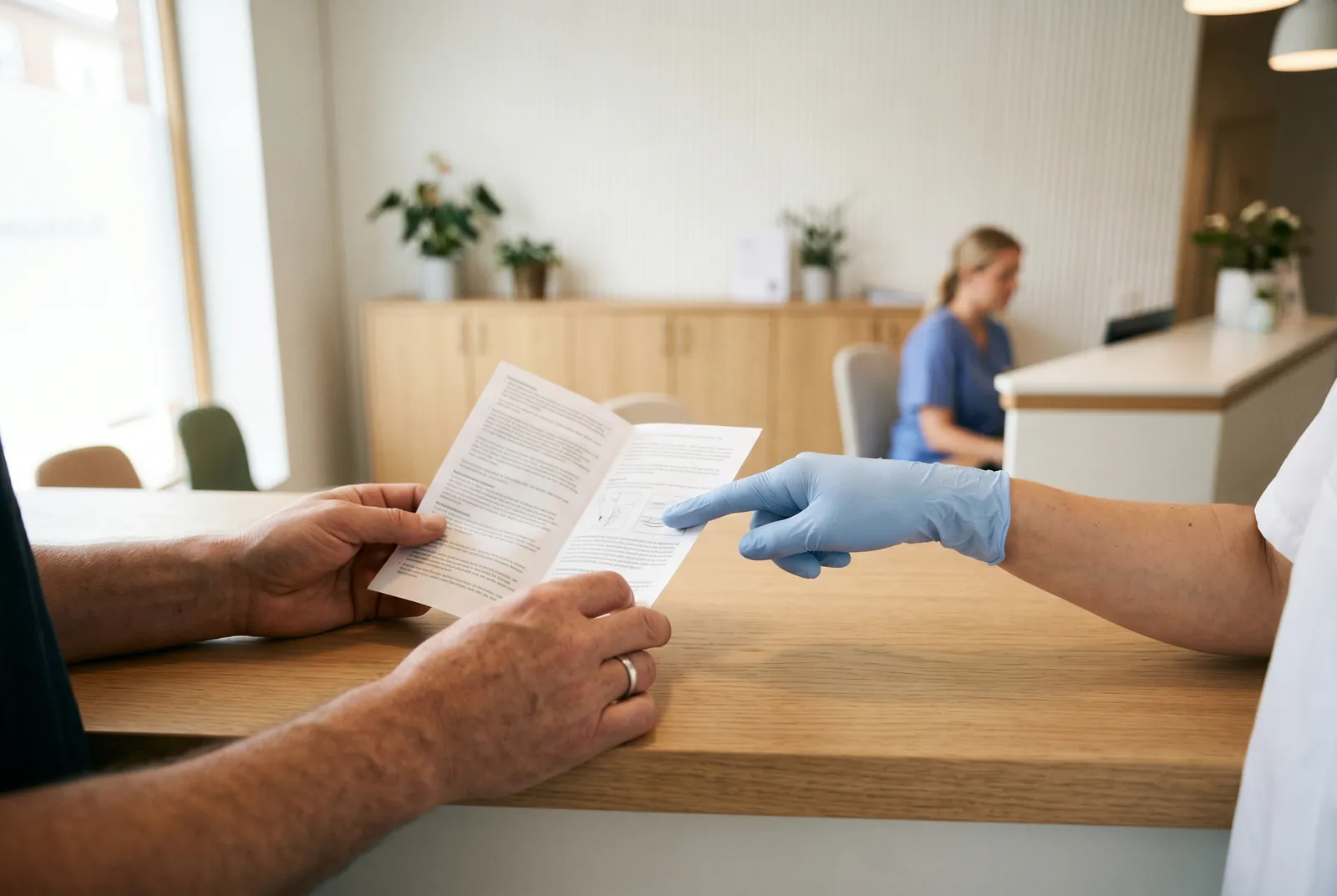 Klient läser informationsblad vid konsultation medan behandlare förklarar